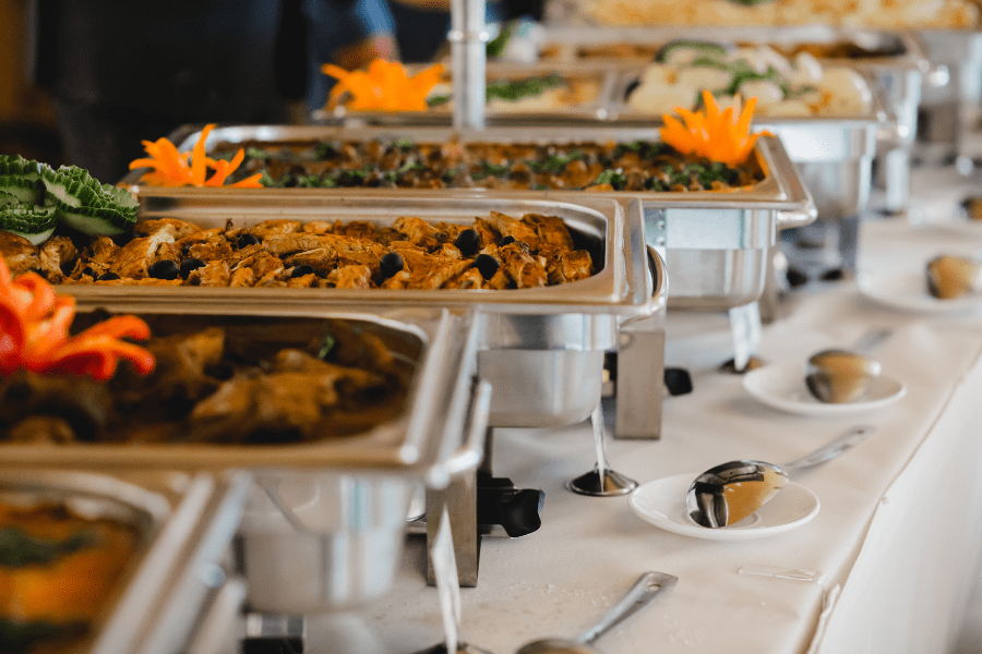 An inviting catering buffet display at Regency O'Fallon, IL, featuring several rectangular chafing dishes filled with a variety of delicious, hot entrees ready to be served.